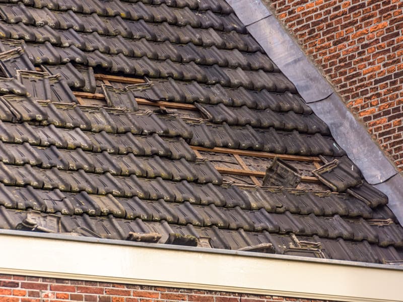 A brick building featuring a broken window, showing emergency roofing services in Manhattan, NY.