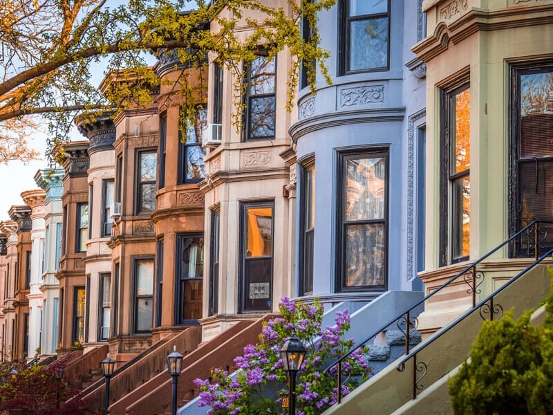 A line of houses with a tree in front, representing a typical street view in a city in Manhattan, NY